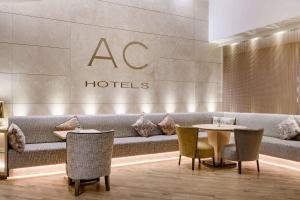 a hotel lobby with tables and chairs and a couch at AC Hotel Genova by Marriott in Genoa