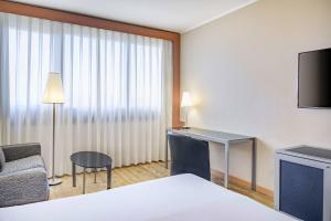 a hotel room with a bed and a desk and a television at AC Hotel Genova by Marriott in Genoa