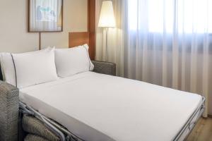 a white bed in a room with a window at AC Hotel Genova by Marriott in Genoa