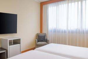 a hotel room with a bed and a chair and a television at AC Hotel Genova by Marriott in Genoa