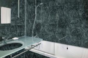 a bathroom with a shower and a sink and a tub at AC Hotel Genova by Marriott in Genoa