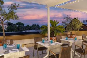 a restaurant with white tables and chairs on a patio at AC Hotel Genova by Marriott in Genoa
