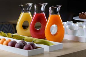 three bottles of juice sitting on a table with fruit at AC Hotel Genova by Marriott in Genoa