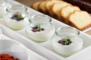 a white tray with four jars of yogurt and berries at AC Hotel Genova by Marriott in Genoa