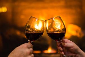 two people holding wine glasses in front of a fireplace at Avila Village Inn in Avila Beach