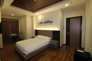 a bedroom with a large white bed and a table at Fair crown Suites in Davao City