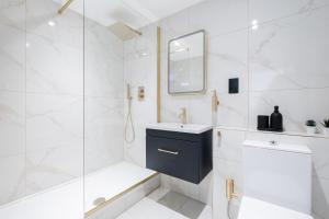 Un baño blanco con lavabo y espejo. en Luxury Apartment in Marylebone, en Londres