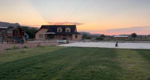 a house with a parking lot with a sunset in the background at Wingate House at Sand Creek Homestead in Torrey