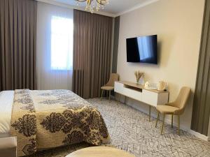 a hotel room with a bed and a desk and a television at DEMIR Hotel in Taraz
