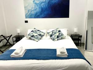 un letto bianco con cuscini bianchi e blu di Lemon tree 400 mt dal mare a Nettuno