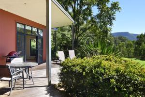 a patio with a table and chairs on a deck at The Heavens Mountain Escape in Kangaroo Valley