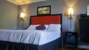 1 dormitorio con 1 cama grande con sábanas blancas y 2 luces en Big A Motel en Orange