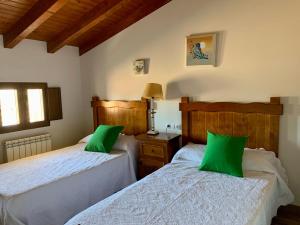 two beds in a room with green pillows at Casa Rural El Gorgocil in Puente del Congosto