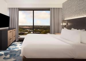 棕榈滩花园Embassy Suites by Hilton Palm Beach Gardens PGA Boulevard的卧室里有一张白色的大床和一扇大窗户