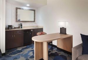 棕榈滩花园Embassy Suites by Hilton Palm Beach Gardens PGA Boulevard的酒店客房配有书桌和带台灯的桌子。