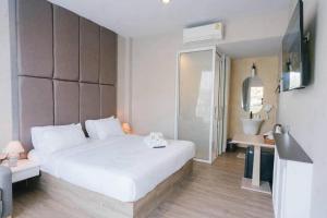 a bedroom with a large white bed and a television at Chergreen cafe & house in Ban Prong Phra Bat Nok
