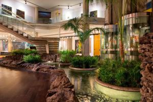 un hall avec un étang planté d'arbres et de plantes dans l'établissement Four Points by Sheraton Catania Hotel, à Catane