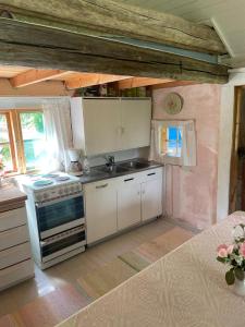 a kitchen with white cabinets and a stove top oven at Valonranta Cottage in Kalmari