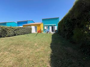 a yard with a yellow and blue house at Maison lumineuse au calme, pres mer in Le Château-dʼOléron