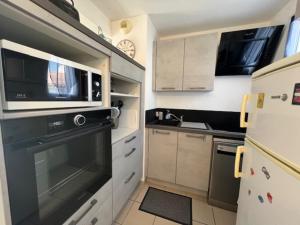 a kitchen with a black oven and a microwave at Maison lumineuse au calme, pres mer in Le Château-dʼOléron