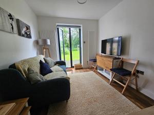 a living room with a couch and a flat screen tv at The Annexe Cheadle Hulme in Cheadle Hulme