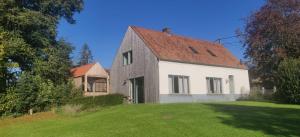 a white house with a red roof on a grass field at De Bossenaarshoeve in Maarkedal