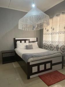 una camera da letto con un letto con un lampadario sopra di Homely Lodge And Apartments a Lilongwe