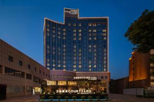 南昌市にあるCourtyard by Marriott Nanchangのバスが前に停まっている高い建物