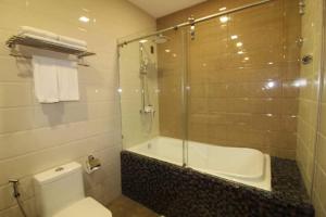 a bathroom with a shower and a toilet and a tub at Fair crown Suites in Davao City
