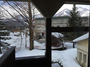 una vista da una finestra di un cortile coperto da neve di Tsugaike Ski House a Otari