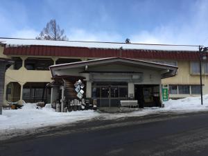 a building on the side of a street with snow at Tsugaike Ski House in Otari