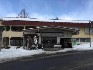 a building on the side of a street with snow at Tsugaike Ski House in Otari