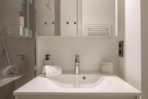 a white bathroom with a sink and a mirror at kindvriendelijk appartement "Sereno", De Haan-Wenduine in Wenduine +19 photos