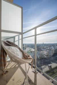 a rattan chair on a balcony with a view of a city at kindvriendelijk appartement "Sereno", De Haan-Wenduine in Wenduine