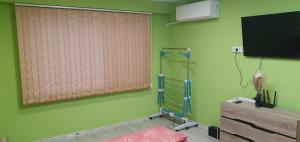 a green room with a shower and a television at Апартамент за гости Краси in Ruse