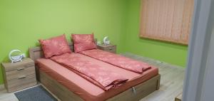 a bedroom with a bed with pink pillows and green walls at Апартамент за гости Краси in Ruse