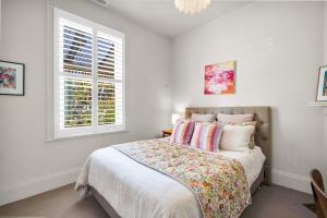 a bedroom with a bed with white walls and a window at Historic 4 Bedroom Townhouse in Launceston