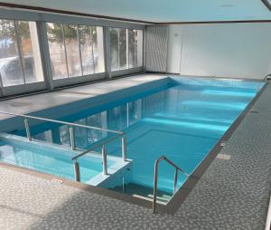 a large blue swimming pool with stairs in a building at Cosy Rooftop Downtown Crans-Montana with Stunning View and Swimming Pool in Crans-Montana