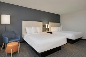 a hotel room with two beds and a chair at Courtyard by Marriott Indianapolis South in Indianapolis