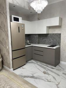 a kitchen with white cabinets and a refrigerator at Apartment 33 in Astana