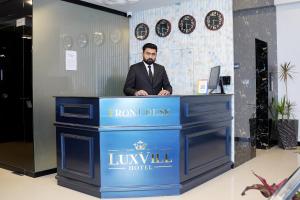 a man is standing at a front desk at Luxvill Hotel in Islamabad