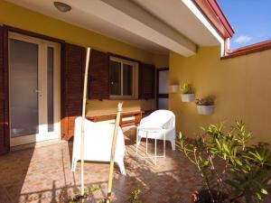 un patio avec deux chaises blanches et une table dans l'établissement Attic With a View, à Fluminimaggiore