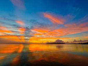 a sunset on the beach with a reflection in the water at Holistic retreat Coco in Ishigaki Island +26 photos