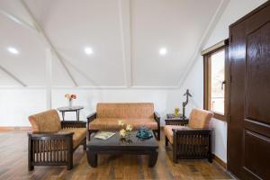 Una sala de estar con un sofá y sillas y una mesa. en Alaya Stays Madhuram Pet-Friendly Hillside Retreat With Garden & Balcony, en Dehradun