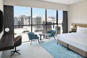 a bedroom with a bed and chairs and a large window at Courtyard by Marriott World Trade Centre, Dubai in Dubai