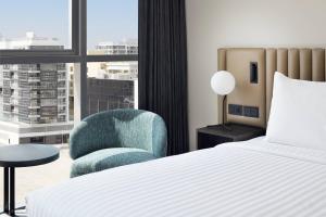 a bedroom with a bed and a chair and a window at Courtyard by Marriott World Trade Centre, Dubai in Dubai