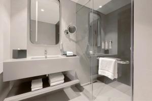 a white bathroom with a sink and a shower at Courtyard by Marriott World Trade Centre, Dubai in Dubai