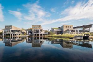 a group of houses on a lake with a sky at Villa Super VIP | 4 Pers. (Villa 5) met jacuzzi, extra kosten voor gebruik in Ouddorp