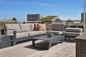 a couch and a coffee table on a deck at Luxe Villa met Uitzicht 4p - Luxe, Rust & Water - Villa 67 in Ouddorp