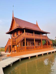 ein großes Holzgebäude neben einem Wasserkörper in der Unterkunft Ruen Singhanat Cafe & Resort in Ban Lum Thonglang (2) + 19 Fotos